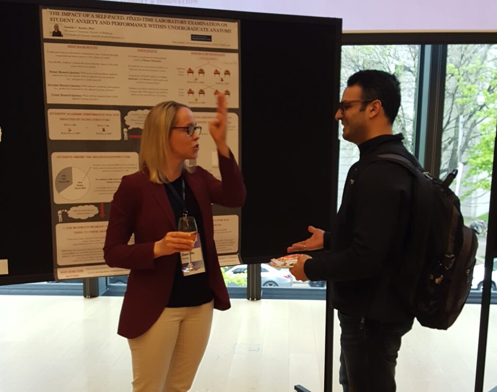 Two people stand talking in front of a research poster