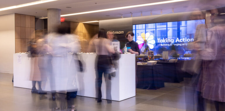 A blurred photo of participants moving near the TLS2023 registration desk